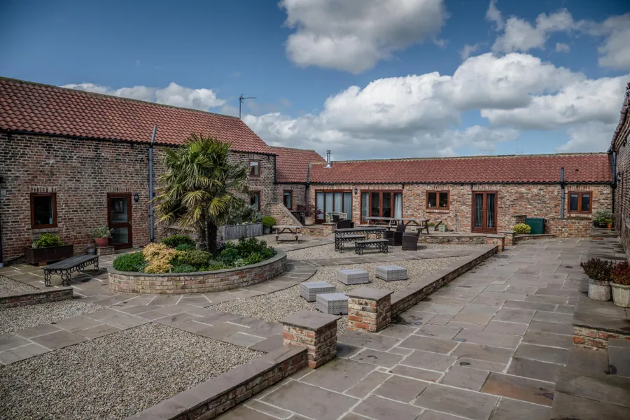 An enclosed courtyard of brick and stone barn ranges with red pantile roofs