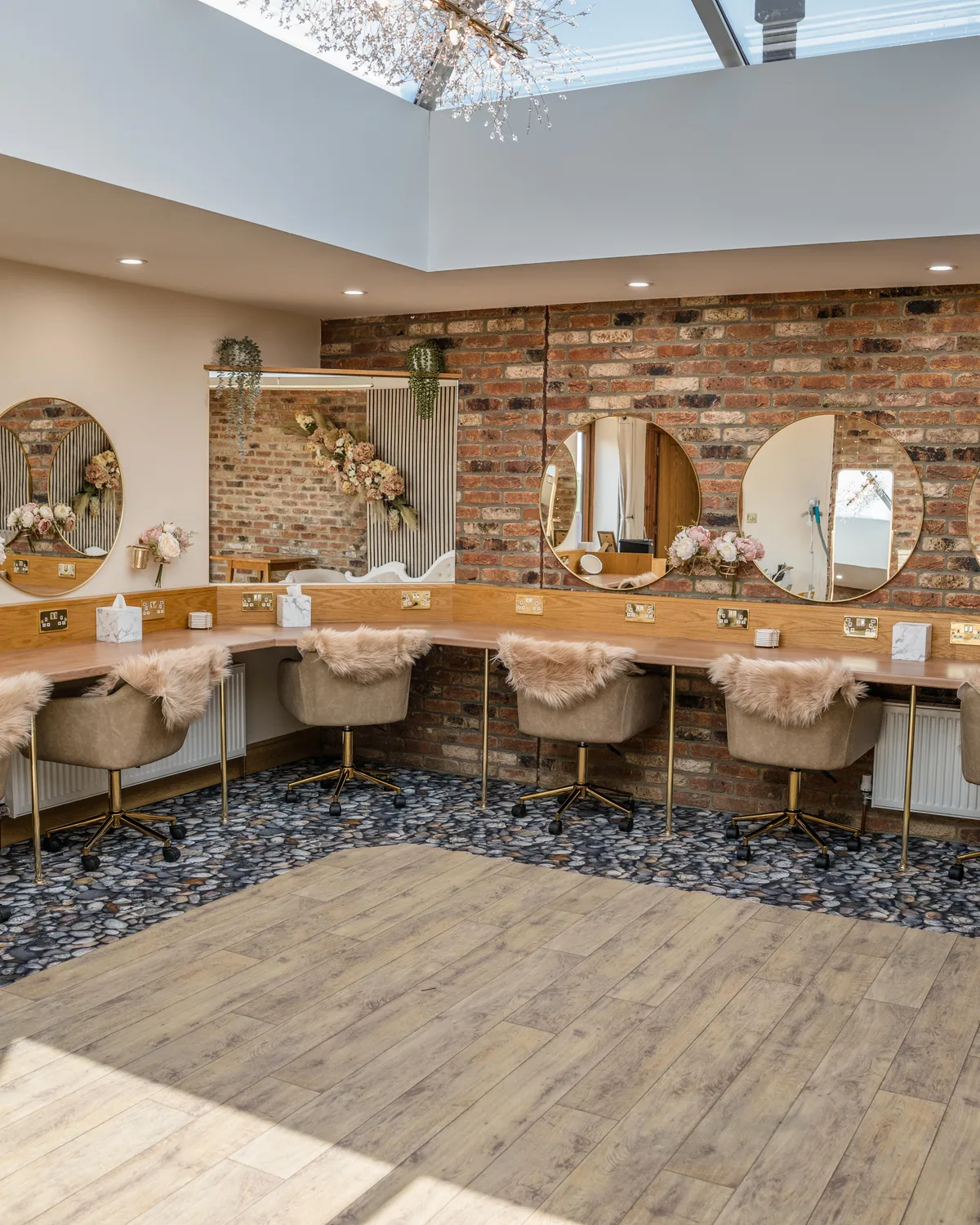 Vanity stations with round lit mirrors under the makeup room skylight