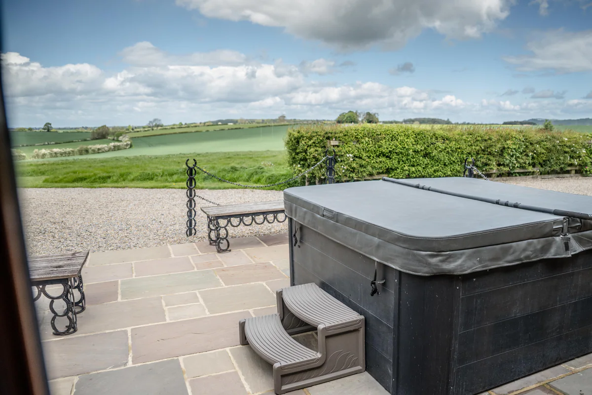 A hot tub on a stone terrace looking out over open fields